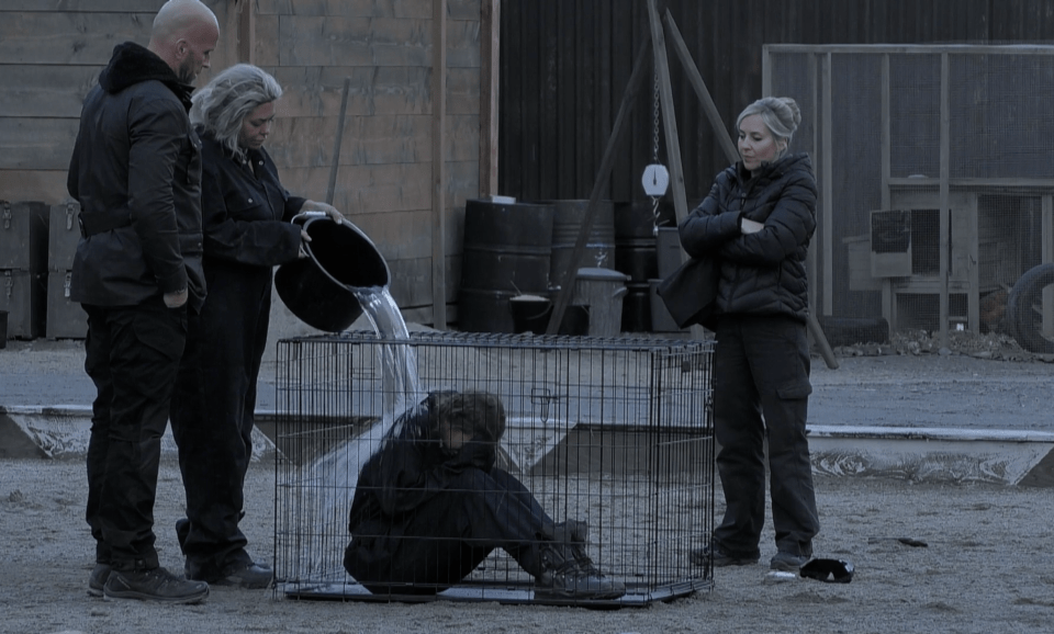 a woman pouring water into a cage while a man watches