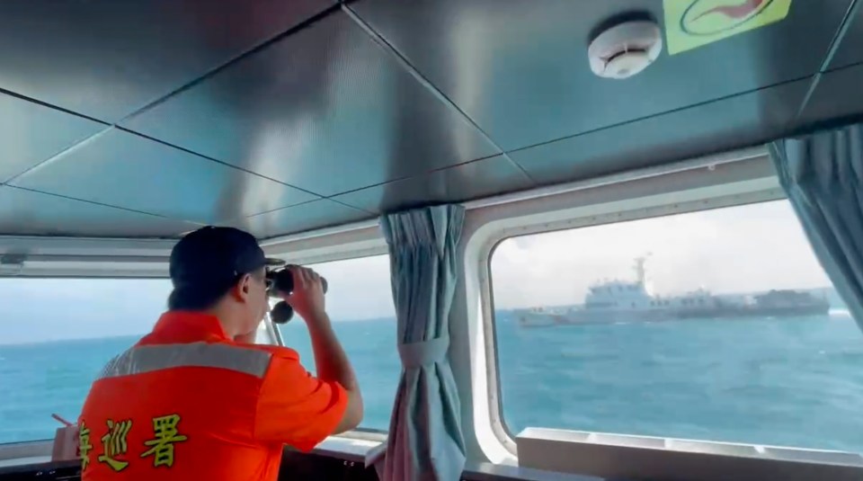 A member of the Taiwan Coast Guard monitors a China Coast Guard vessel as it passes near the coast of Matsu islands