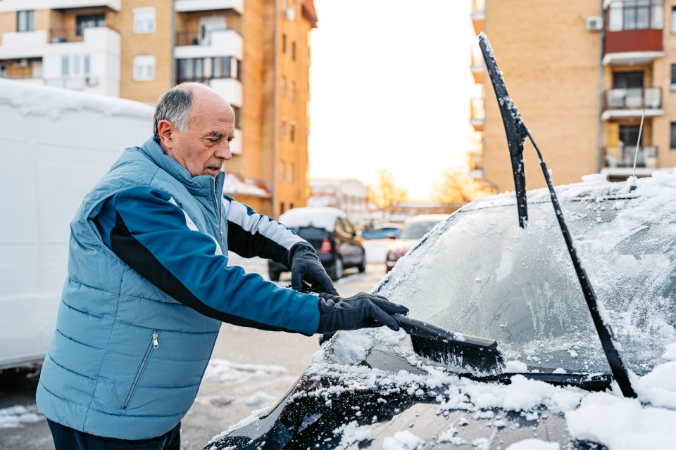 a man in a blue vest is cleaning the windshield of his car