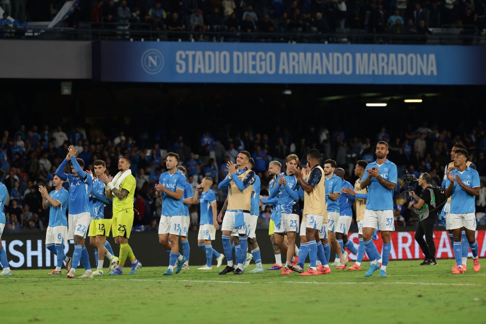 a group of soccer players applaud in front of a sign that says stadio diego armando maradona