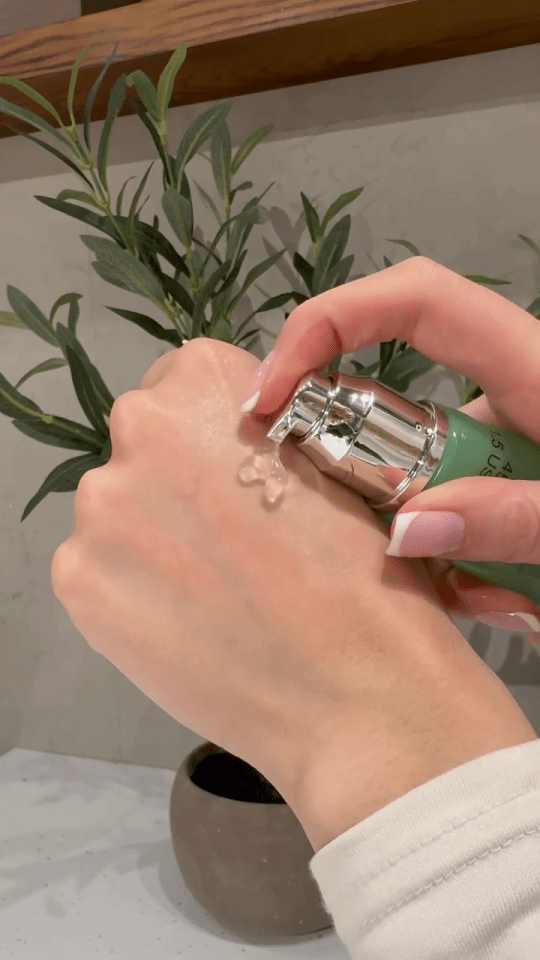 a woman is applying a green bottle of lotion to her hand