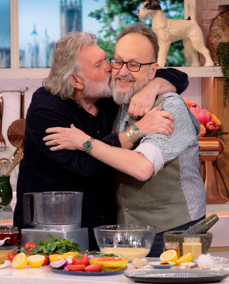 a man kisses another man on the cheek in a kitchen