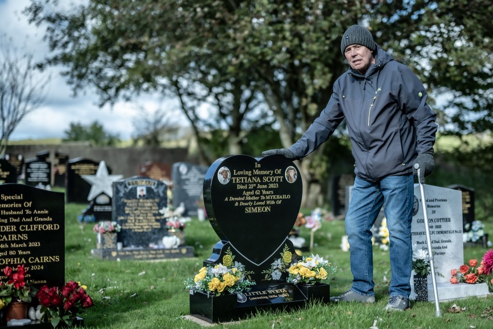 Grieving pensioner Simeon next to his wife Tetiana's grave