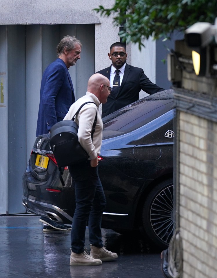 a man in a suit and tie is standing next to a black maybach car