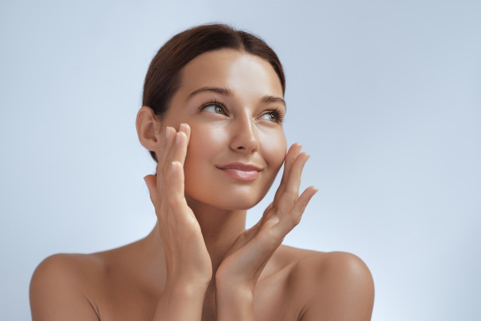 a woman is touching her face with her hands and smiling