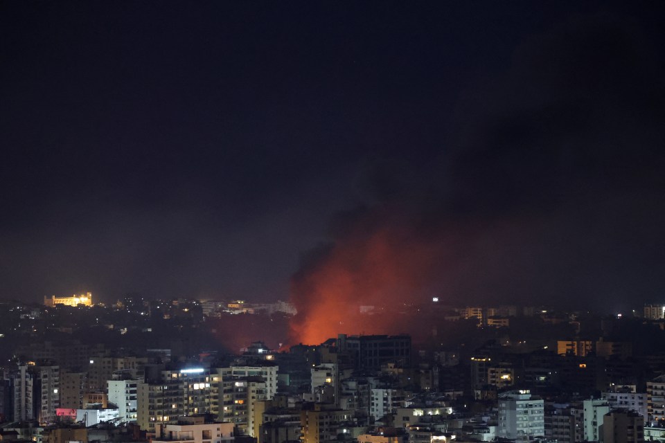 a city at night with smoke coming out of a building