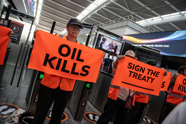 a man holding an orange sign that says " oil kills "