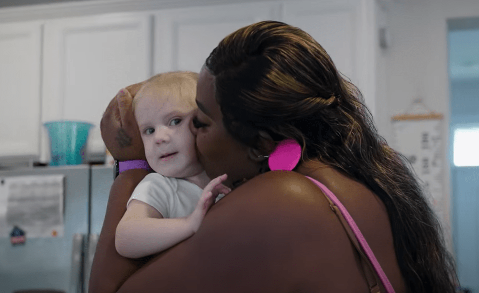 a woman with pink earrings is holding a baby