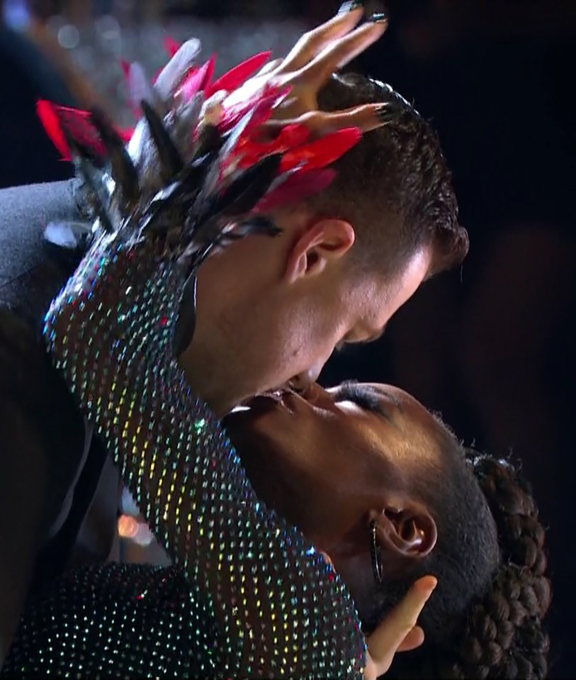 a man and a woman are kissing in front of a crowd