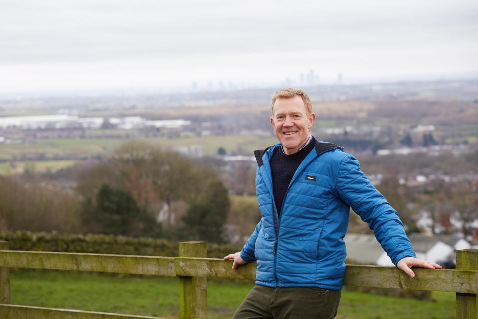 a man leaning on a wooden fence with a city in the background