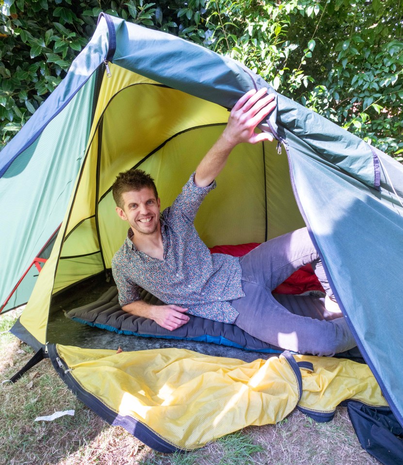 a man laying in a tent with his arm outstretched