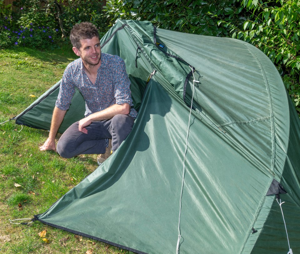 a man is kneeling in front of a green tent