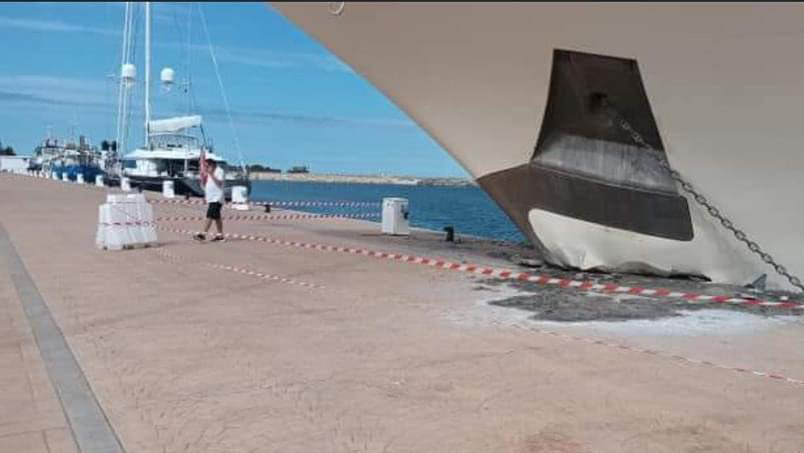 a man is standing next to a boat that has been damaged in a harbor .