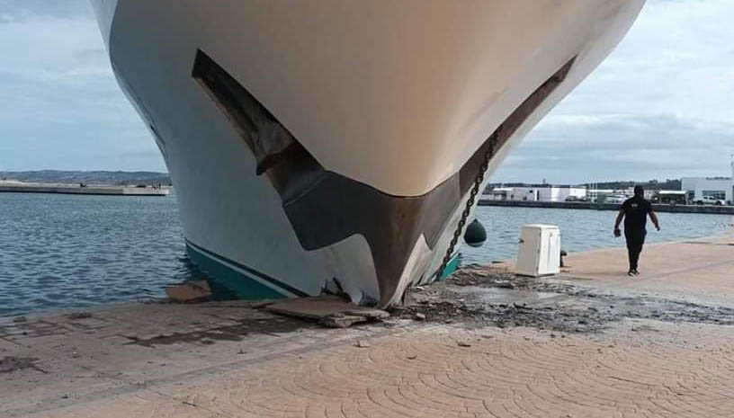 a man is walking past a large boat that has fallen into the water .