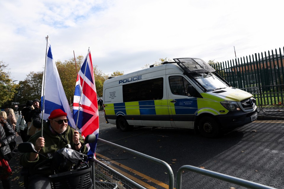 a man holds a flag in front of a police van