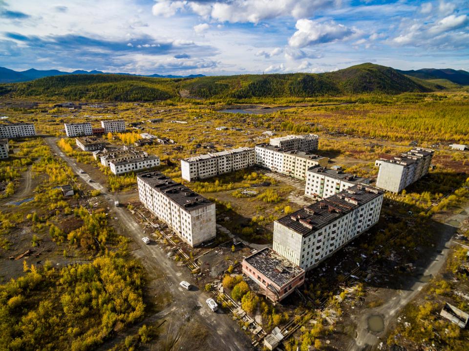 an aerial view of an abandoned city with mountains in the background