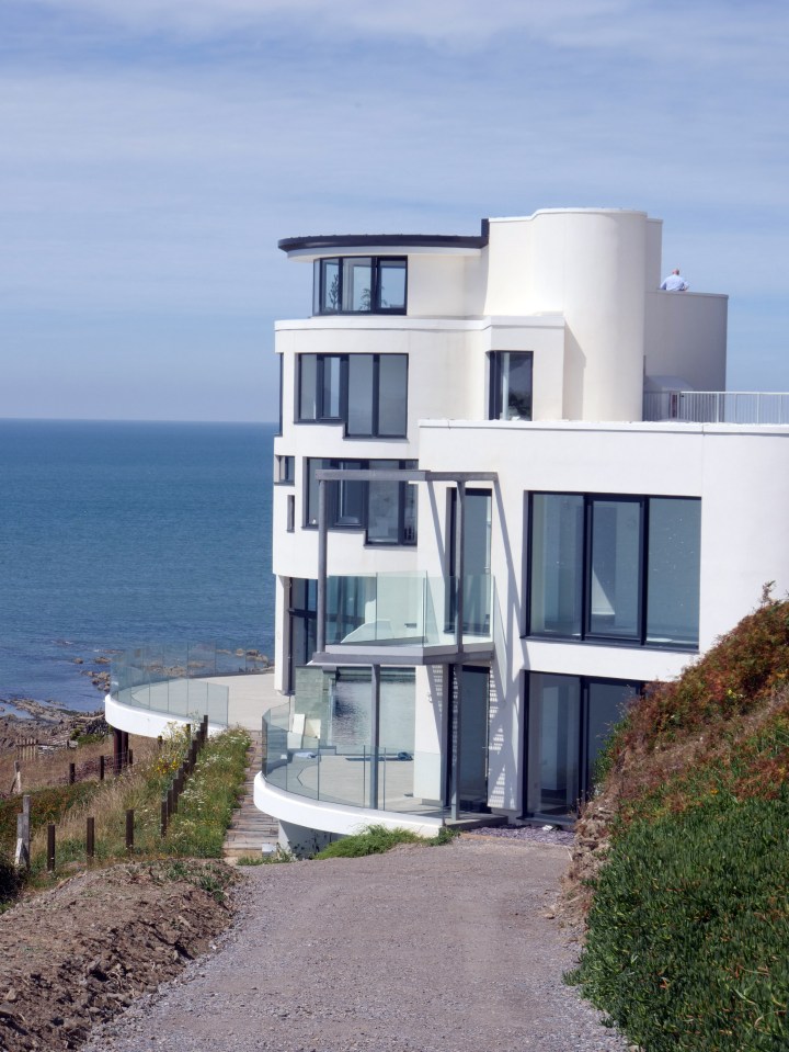 a large white house with a balcony overlooking the ocean