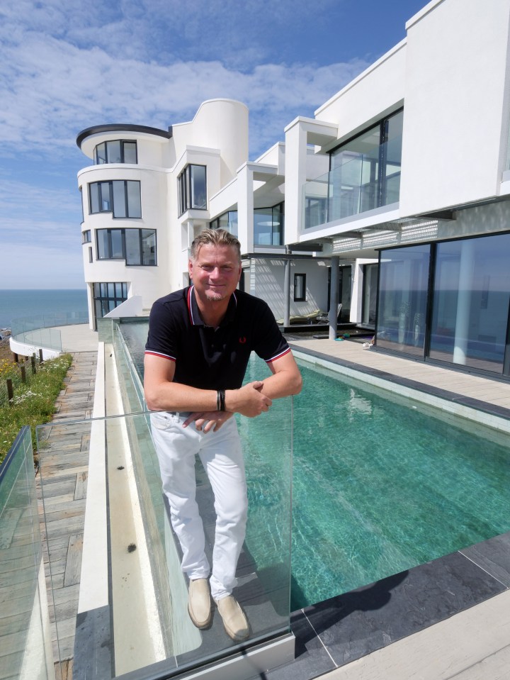 a man stands on a balcony overlooking a swimming pool