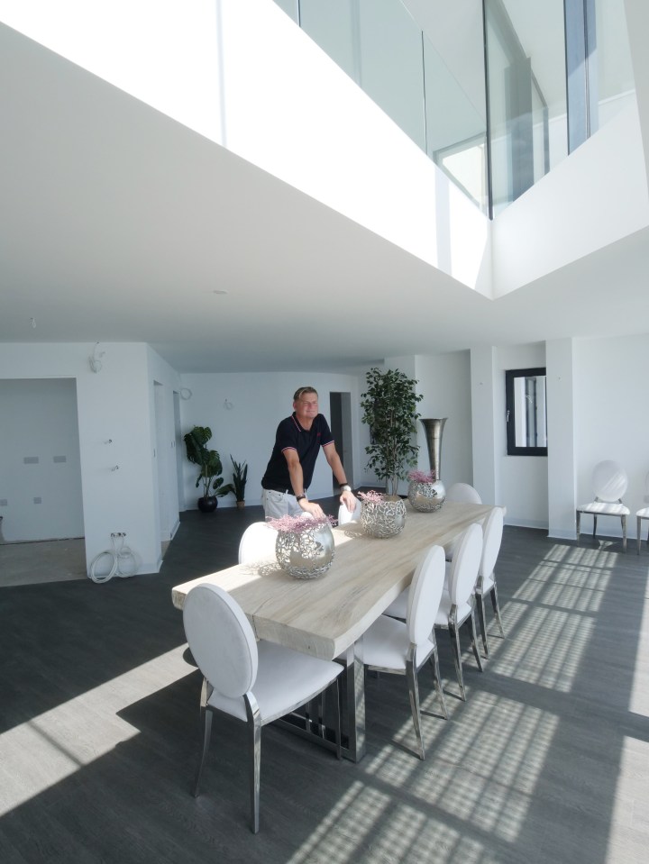 a man stands in a dining room with a table and chairs