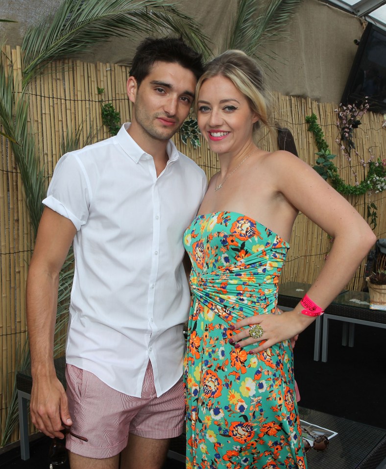 a man in a white shirt and pink shorts stands next to a woman in a floral dress