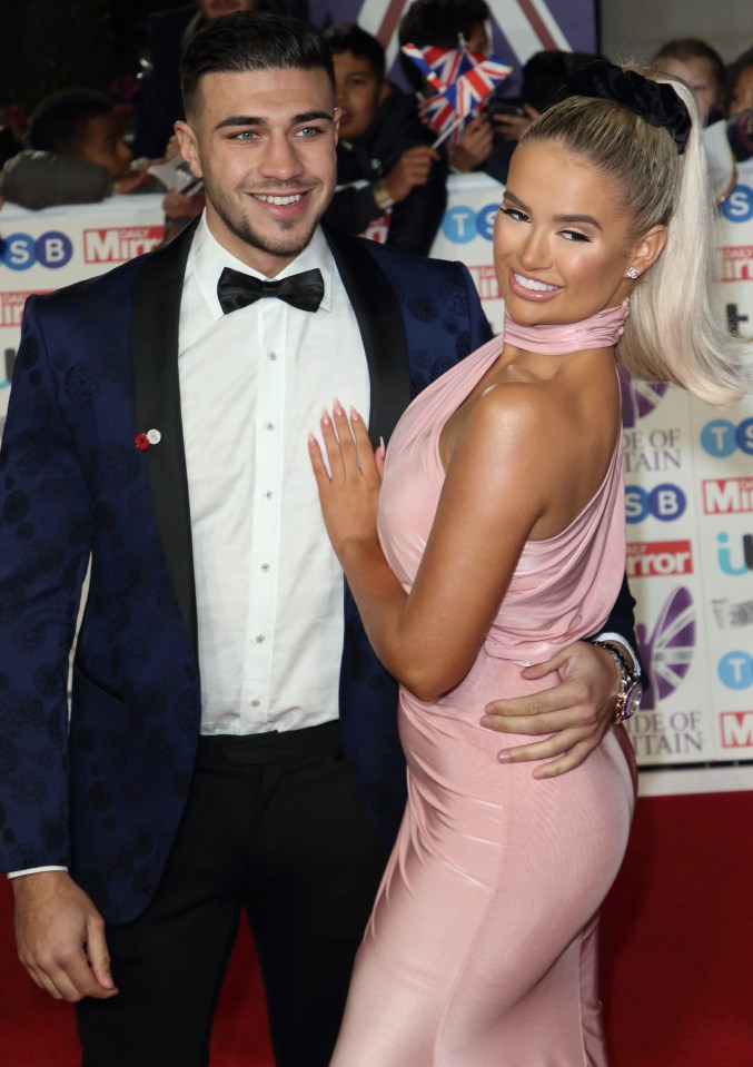 a man in a tuxedo and a woman in a pink dress pose on a red carpet