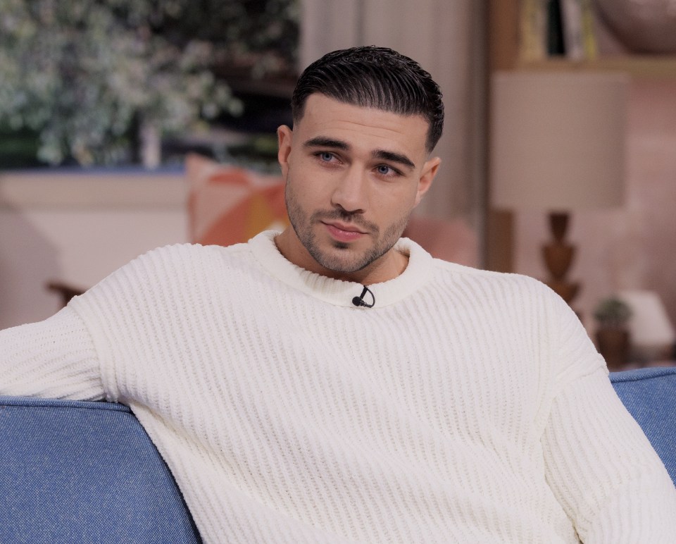 a man in a white sweater sits on a blue couch