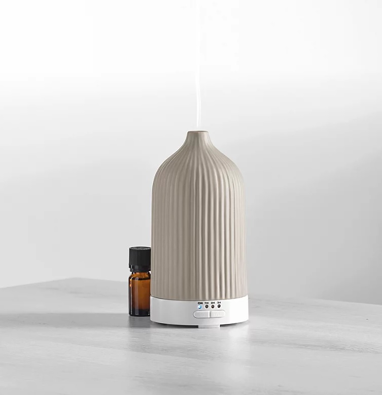 a bottle of essential oil sits next to a diffuser on a table