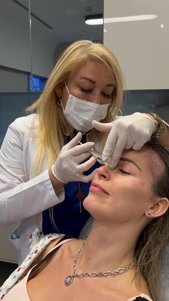 a woman wearing a mask and gloves is getting an injection