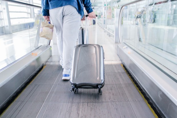 a person walking down an escalator with a suitcase