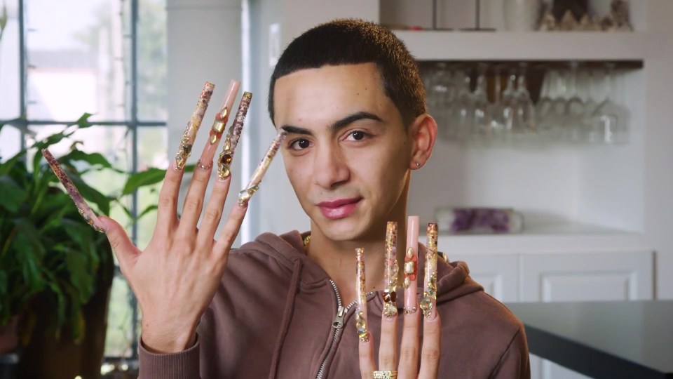 a man with very long nails is wearing a brown hoodie