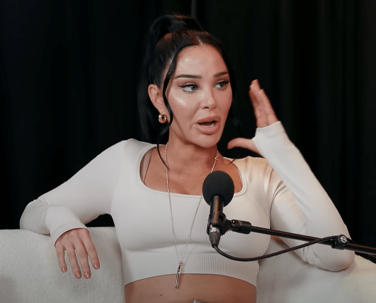 a woman in a white crop top sits in front of a microphone