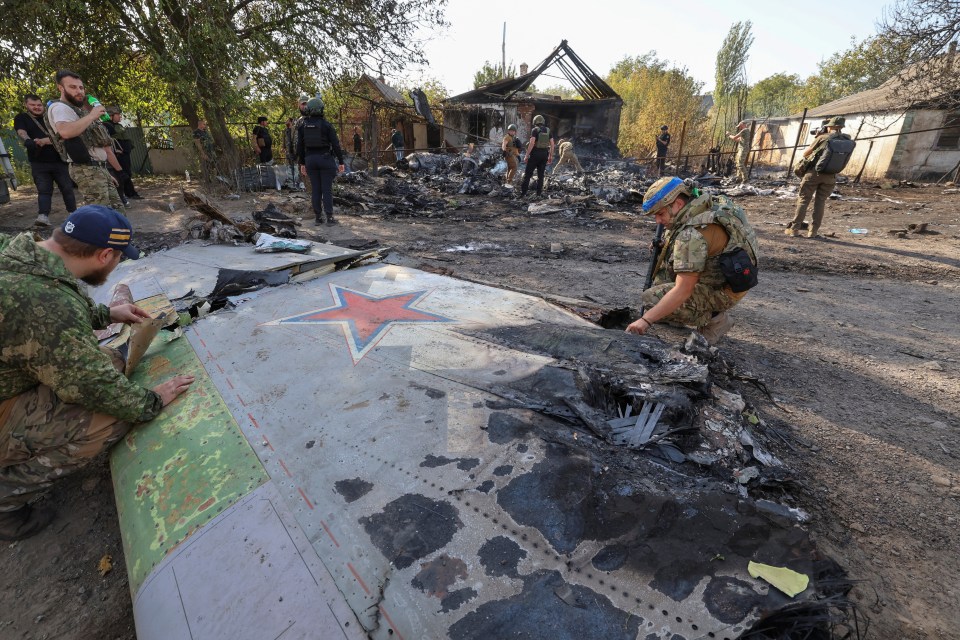 Ukrainian service members inspect parts of a Russian aerial vehicle which could unlock military secrets