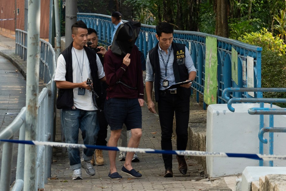 a man wearing a mask is being escorted by police officers