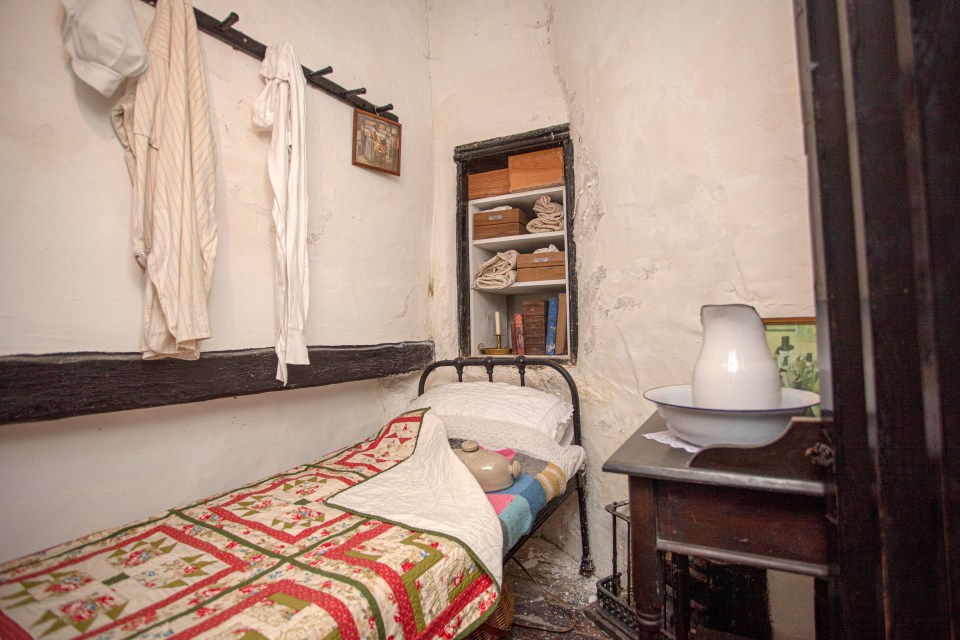 a small bedroom with a quilted bed and a pitcher on a table