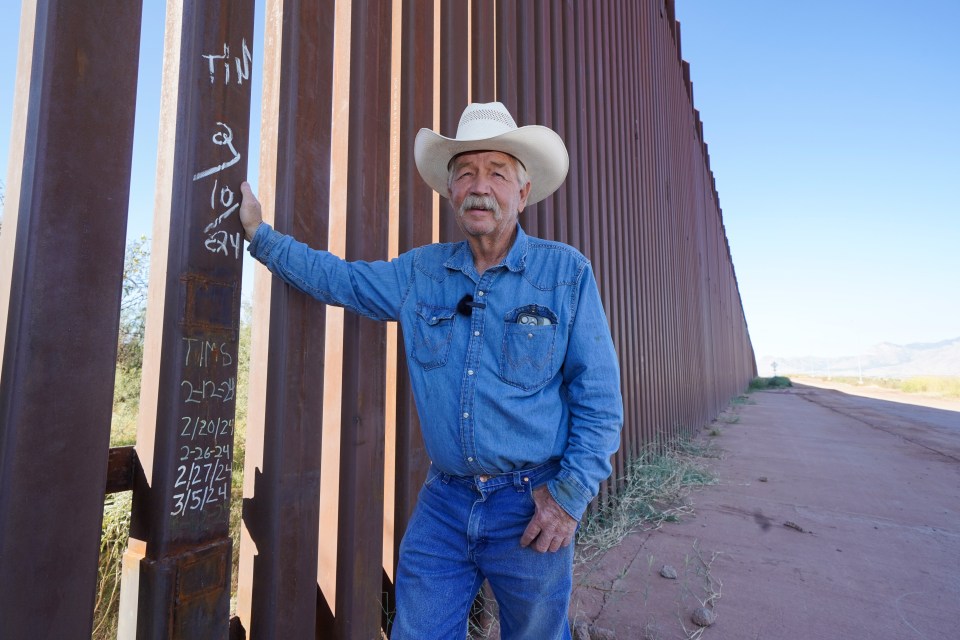 Arizona rancher John Ladd stands by the metal wall between America and Mexico