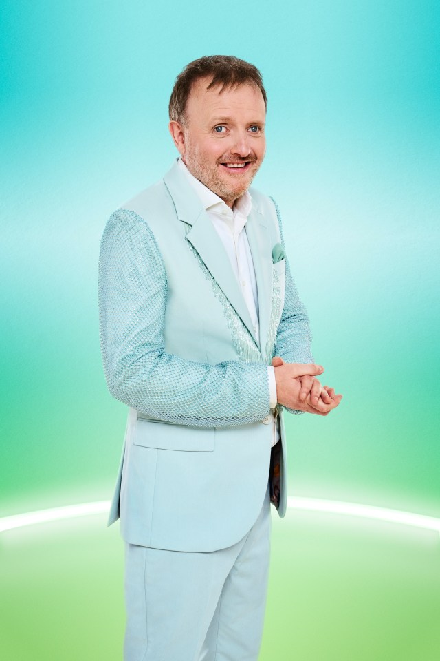 a man in a light blue suit stands with his hands folded