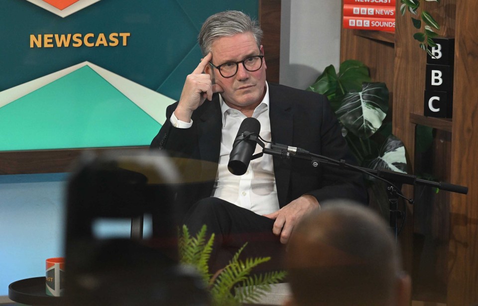 a man sitting in front of a microphone in front of a sign that says newscast