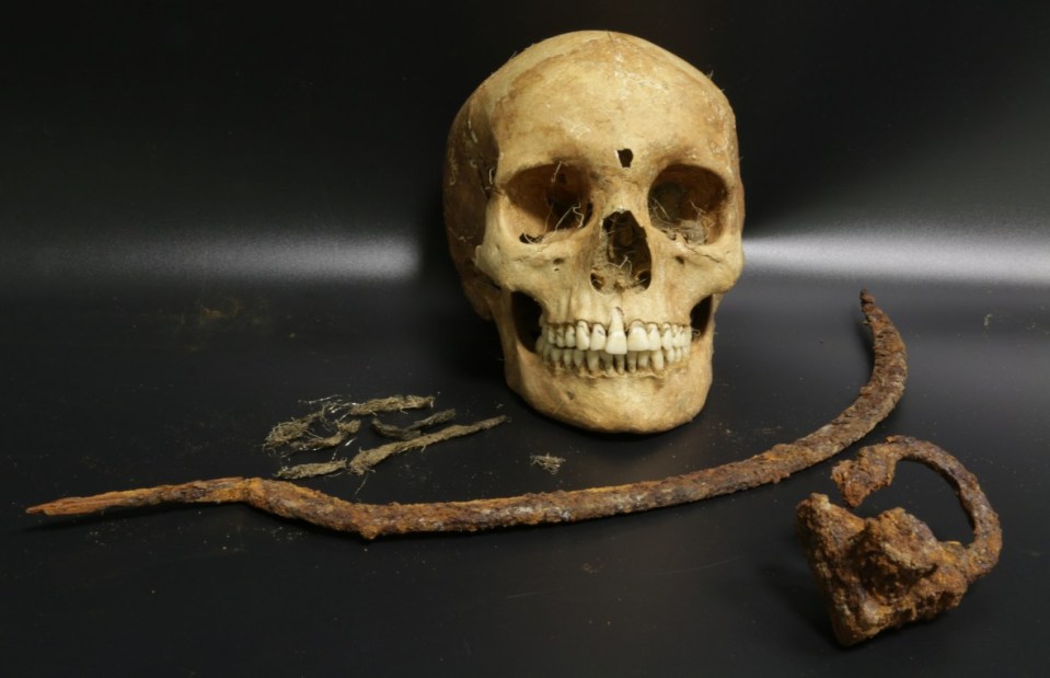 a skull and a rusty object on a black surface