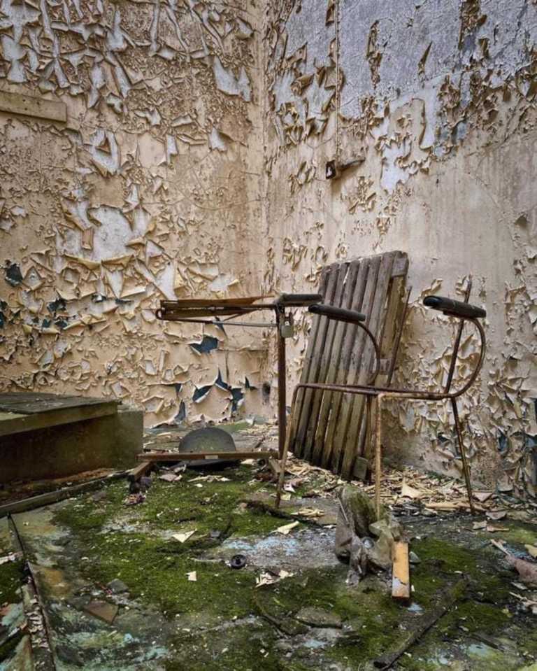 a chair sits in a room with peeling paint on the walls