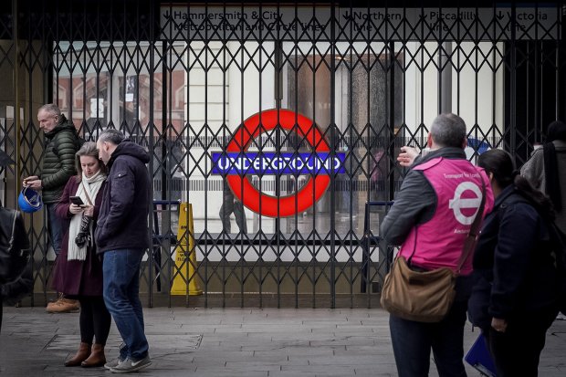 a group of people standing in front of an underground sign