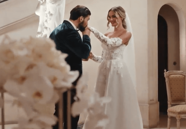 a bride and groom are standing next to each other and the groom is touching the bride 's hand