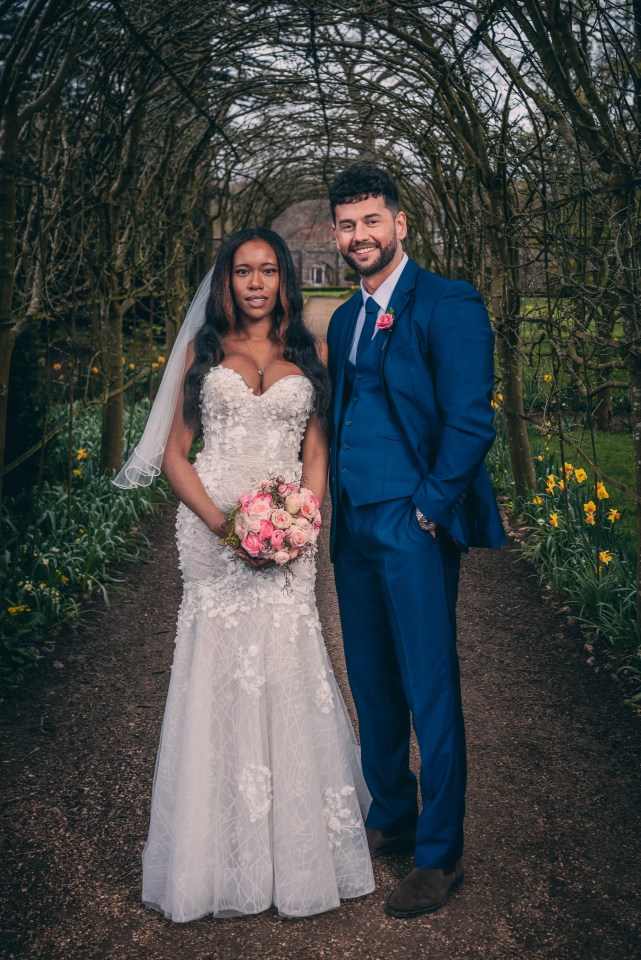 a bride and groom pose for a picture under a tree archway