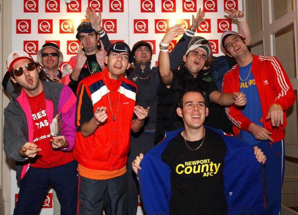 a group of men are posing for a picture and one of them is wearing a newport county afc shirt