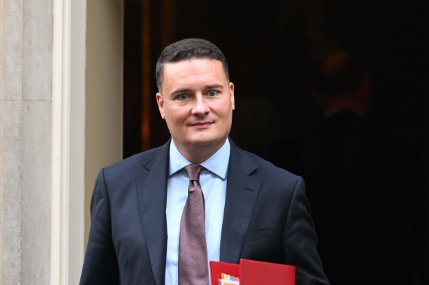 a man in a suit and tie is holding a red folder