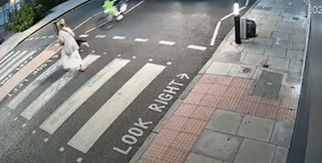 a woman is walking across a crosswalk with a sign that says look right .