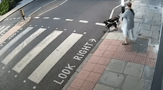 a woman is walking a dog across a crosswalk with a sign that says look right .