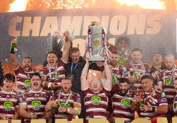 a group of men holding a trophy in front of a sign that says champions