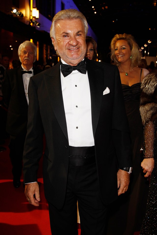 a man in a tuxedo stands on a red carpet