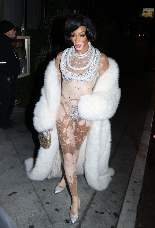 a woman wearing a fur coat and a bodysuit with rhinestones