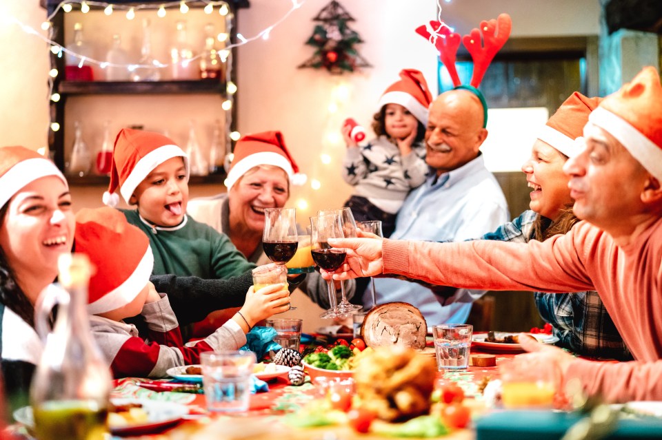 a group of people wearing santa hats are toasting with wine glasses